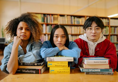 A group of diverse students engaging in studies at a library, surrounded by books and resources.